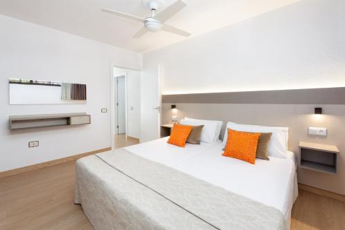 ein Schlafzimmer mit einem großen weißen Bett mit orangefarbenen Kissen in der Unterkunft Aguamar Apartamentos, Los Cristianos Downtown in Los Cristianos