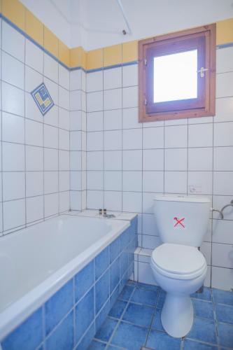a bathroom with a toilet and a tub and a window at Pilio Sea Horizon Hotel in Tsagarada