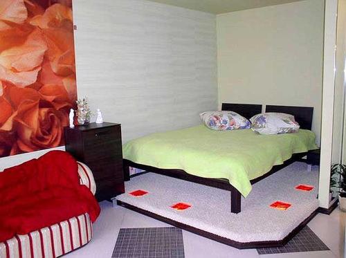 ヘルソンにあるDzhon Govard Studioのベッドルーム1室(ベッド1台、赤い椅子付)