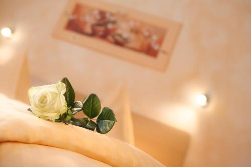 une rose blanche assise au-dessus d'un lit dans l'établissement Hotel Mediterraneo, à Neustadt an der Weinstraße