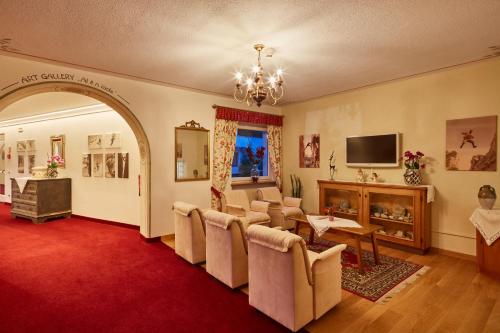 a living room with a red carpet and a waiting room with chairs at Dolomites Wellness Hotel Savoy in La Villa
