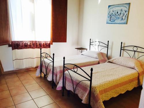 twee bedden in een kamer met een raam bij Agriturismo Santu Marcialis in Dolianova
