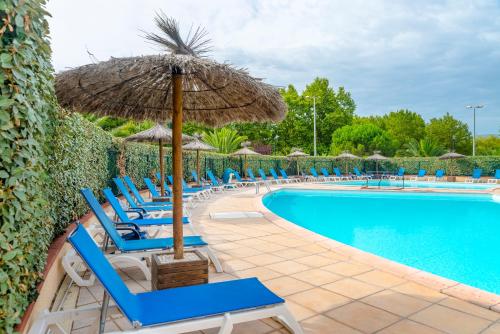 eine Gruppe von Stühlen mit einem Sonnenschirm und einem Pool in der Unterkunft Azureva Saint Cyprien in Saint-Cyprien