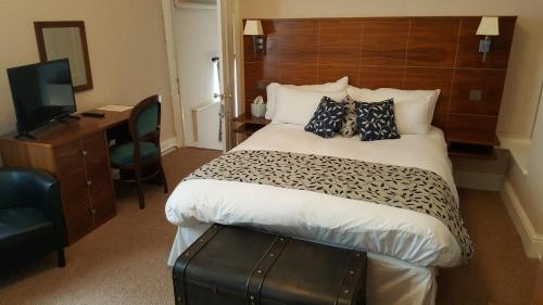 a hotel room with a bed and a desk and a television at The Greyhound Hotel Cromford in Cromford