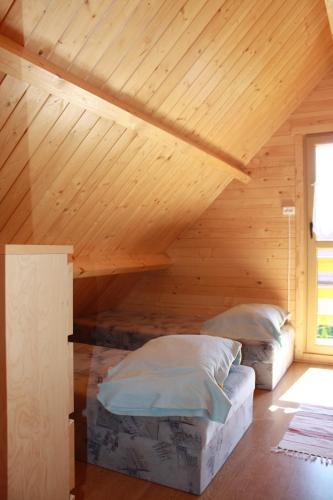 two beds in a room with a wooden ceiling at Domki Pod Lasem in Polańczyk