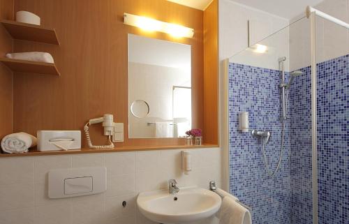 ein Bad mit einem Waschbecken und einer Dusche mit einem Spiegel in der Unterkunft Hotel Haus Chorin in Chorin