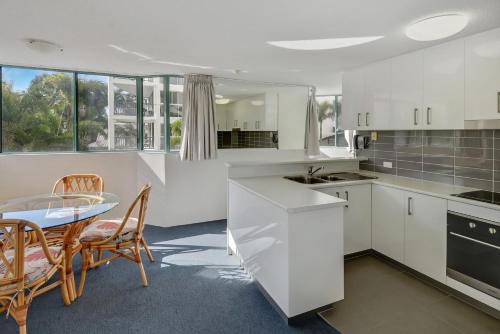 a kitchen and dining room with a table and chairs at Excellsior Apartments in Mooloolaba