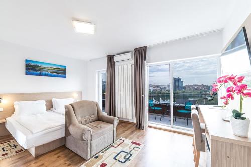 a hotel room with a bed and a chair and a window at Residence iL Lago in Cluj-Napoca