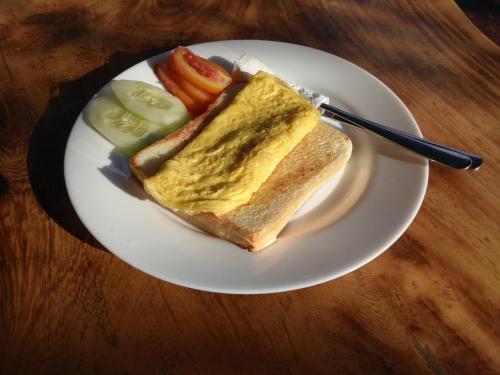 a white plate with a sandwich and pickles on a table at Yasa Homestay in Nusa Penida