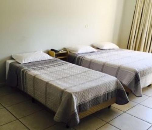 two beds sitting next to each other in a room at Hotel Huesca in Presidente Prudente
