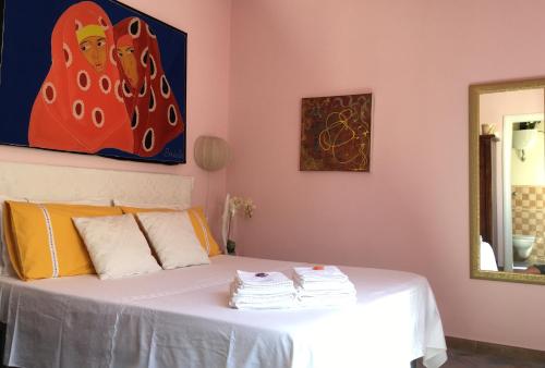 a bedroom with a white bed with a painting on the wall at Bogamarì in Alghero
