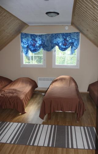 two beds in a room with two windows at Surkeenjärven Jaakon talot in Moksinkylä