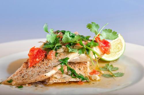 a plate of food with a piece of fish with a lime at Hotel Cristal Park in Dąbrowa Tarnowska