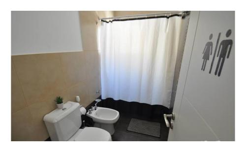 een badkamer met een toilet en een wit douchegordijn bij Casa Ba Haus in Puerto Pirámides