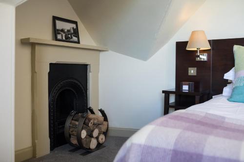 a bedroom with a fireplace next to a bed at Nether Abbey Hotel in North Berwick