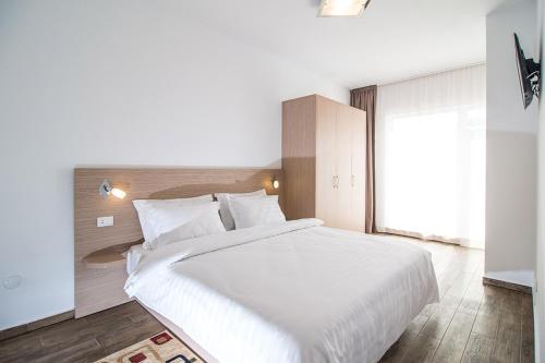 a bedroom with a large white bed and a window at Residence iL Lago in Cluj-Napoca