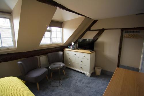 - une chambre avec un lit et une commode avec une télévision dans l'établissement Church Inn, à Ludlow