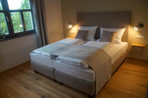 una camera da letto con un grande letto con lenzuola e cuscini bianchi di Hotel Dorfmühle a Lehrberg