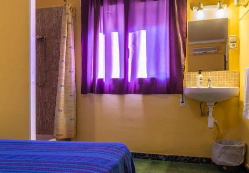 een badkamer met een wastafel en een raam met paarse gordijnen bij Hostal Urgell in Balaguer