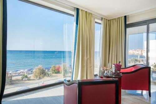 a room with a table and chairs and a view of the ocean at Victoria Palace Cefalù in Cefalù