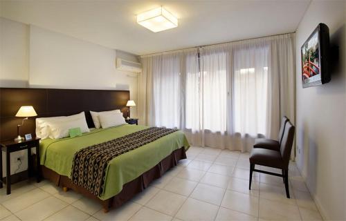 Un dormitorio con una cama y una silla y una ventana. en Piccaluga Apartments, en Buenos Aires
