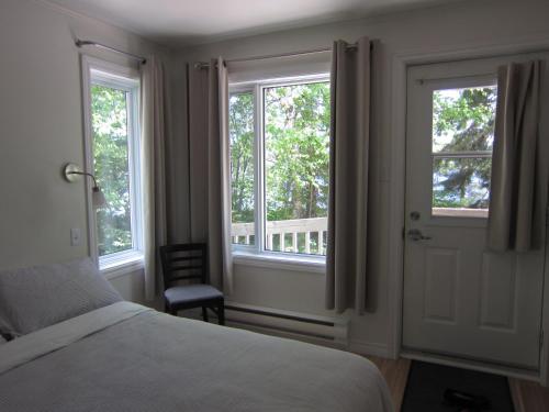 a bedroom with two windows and a bed and a chair at Auberge Île du Repos in Honfleur