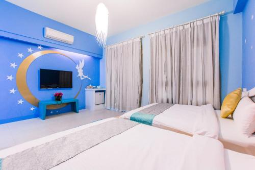 a blue bedroom with two beds and a tv at Capri Homestay in Hualien City