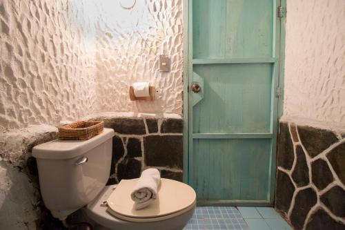 baño con aseo y puerta azul en Eco Hotel Uxlabil Atitlan en San Juan La Laguna
