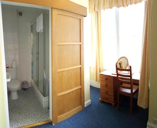a bathroom with a shower and a toilet and a wooden door at The Ratcliffe Guest House in Paignton