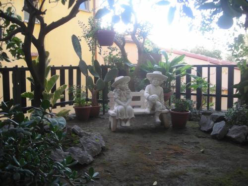 two statues sitting on a bench in a garden at B&B L'Arcobaleno in Sorrento