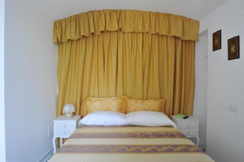 a bedroom with a bed with a yellow curtain at Surriento Suites in Sorrento