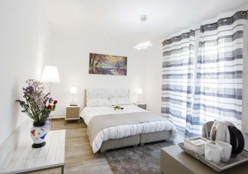 a white bedroom with a bed and a vase of flowers at B&B Stella Maggiore in Verbania