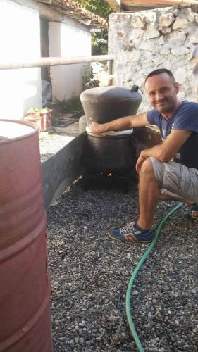 a man sitting next to a tire with a hose at Eco Garten Guest House in Shkodër