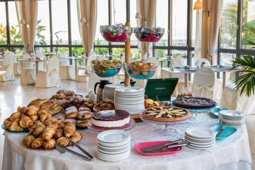 a table topped with plates and cakes and pastries at Hotel Riviera dei Fiori in San Lorenzo al Mare