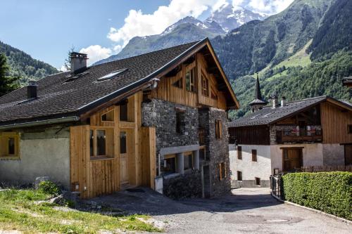 una casa con puertas de madera y montañas en el fondo en Le petit Saint Bernard, en Sainte-Foy-Tarentaise