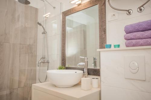 a bathroom with a sink and a mirror and purple towels at Hostel Splendido in Šibenik