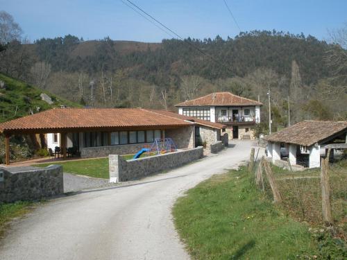 uma estrada de terra em frente a dois edifícios com uma casa em El Molin De Frieras em Posada de Llanes