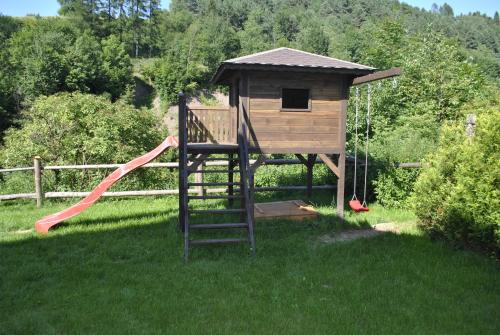 un parco giochi con scivolo e una casetta per i giochi di Aparthola a Szczawnica