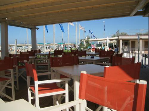 リド・ディ・カマイオーレにあるStabilimento balneare Bragozzoのテーブルと椅子と旗が並ぶ空きレストランです。