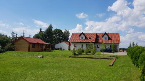 a house with a red roof on a green yard at Gościniec Mazurek in Giżycko