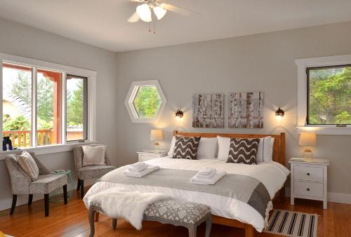 a bedroom with a bed with two chairs and two windows at Sunshine Villa B&B in Madeira Park