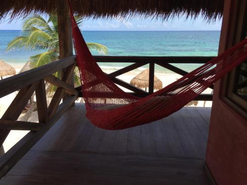a red hammock hanging from a thatched porch overlooking the beach at La Conchita Tulum in Tulum