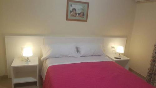 ein Schlafzimmer mit einem rosa Bett mit zwei Nachttischen in der Unterkunft Apartamento Avenida in Puerto de Santiago