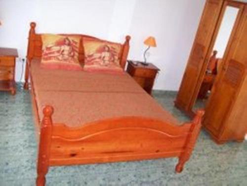 a bedroom with a wooden bed with orange sheets at El Rancho in Grand-Bourg