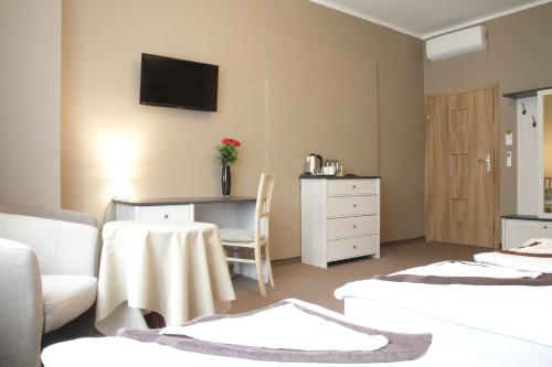 a room with two beds and a desk with a tv on the wall at Rest- Pokoje z Łazienkami in Gdynia