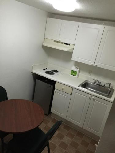a kitchen with white cabinets and a sink and a table at Extended Stay Studios in Montgomery