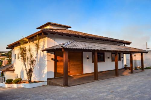 a white house with a tile roof at Lara's Home Suites in Capitólio