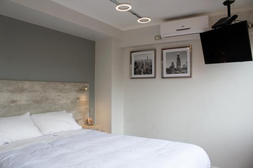 a bedroom with a white bed and a flat screen tv at Amg Apartments in Santiago