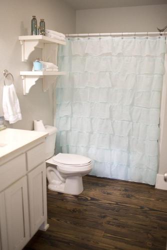 a bathroom with a toilet and a white shower curtain at Stonehill Cottages in Mena