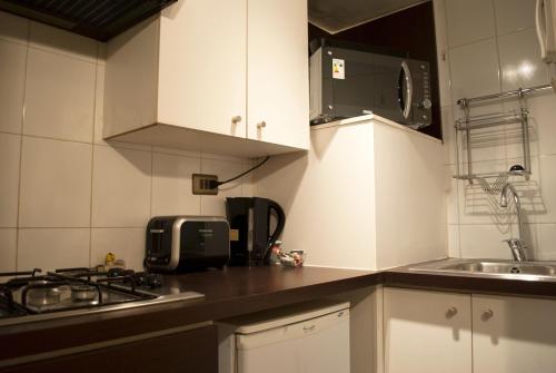 cocina con armarios blancos, fregadero y fogones en Amg Apartments San Sebastian, en Santiago